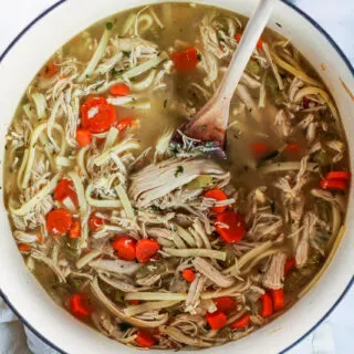 a white dutch oven of chicken noodle soup