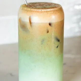 pumpkin matcha in a glass with vanilla protein shake topped with matcha, swirled together, then topped with pumpkin cold brew